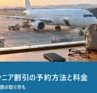 朝の空港の窓から見える旅客機と、カウンターに置いたスマートフォン・老眼鏡